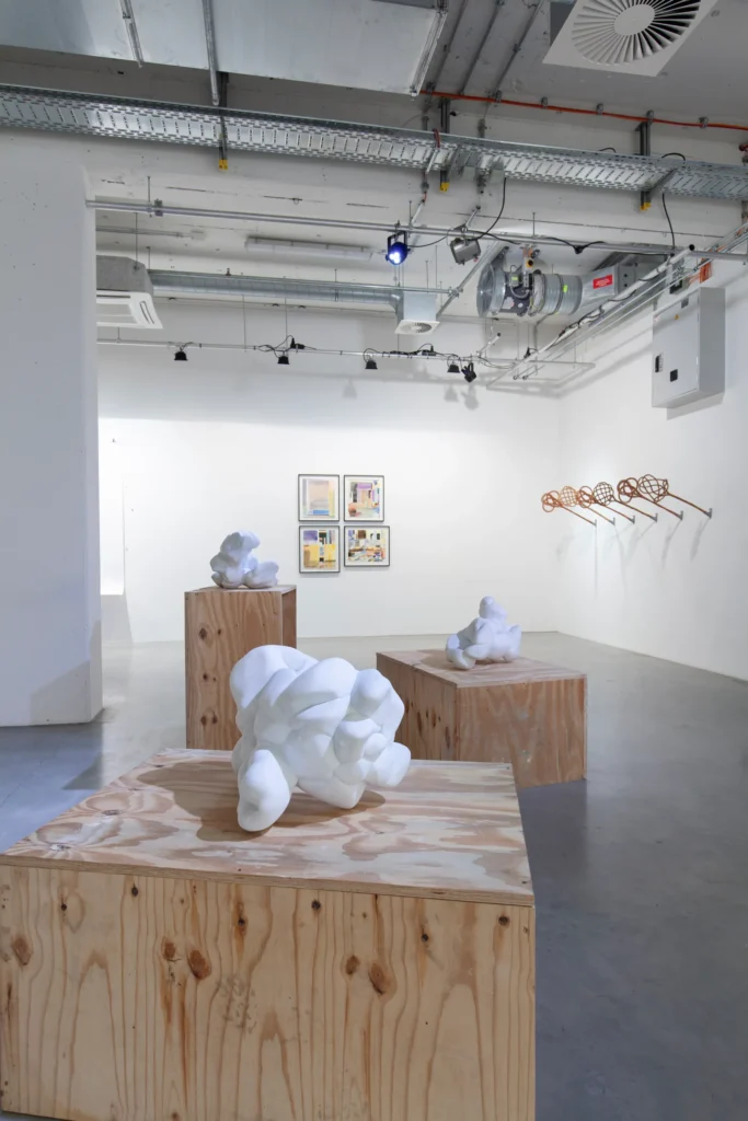 Vordergrund: Marmor-Skkulpturen von Gregor Passens „Popcorn #1 – #3“. Im Hintergrund links: Malerei von Angela Stauber „so so“, „so da“, „so nah“ und „so fort“. Hintergrund rechts: Installation von Anette Olbrich: „Ordnungsgeflechte“.